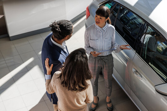 Couple learning about details of a car from a salesperson