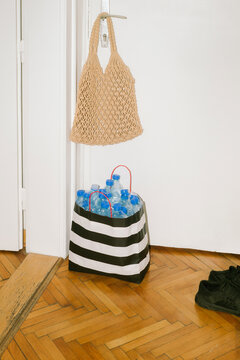 A bag of crumpled plastic bottles stands by the front door
