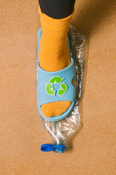 Female foot crushes a plastic bottle before sending it for recycling