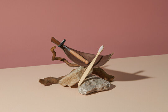 Wooden toothbrush and razors on a pink background. 