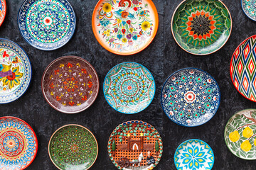 Ancient traditional Uzbek utensils - plates at the wall. With national floral ornament