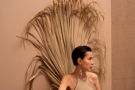 Profile of young woman against dry palm leaf