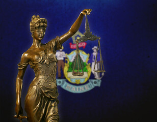 Lady Justice before a flag of Maine