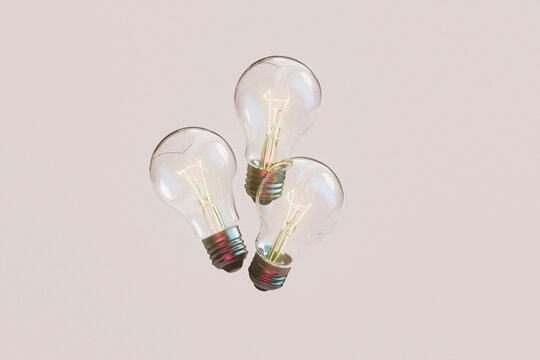Trio of Glowing Light Bulbs on Pastel Pink Background
