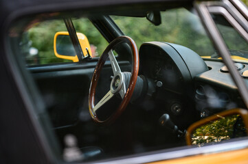 Close-up of the interior of a vintage yellow convertible car, showcasing a wooden steering wheel...