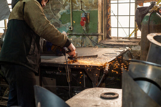 Worker with a grinder in production