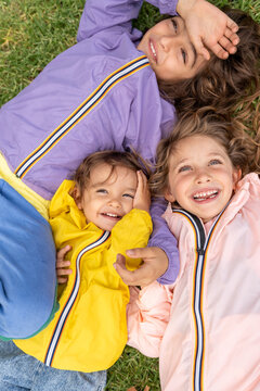 kids laying down together on the grace with colourful jackets