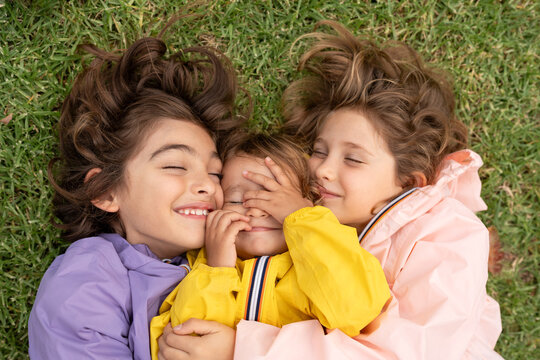 kids laying down together on the grace with colourful jackets