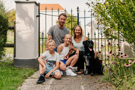 Happy family with dog sitting by gate