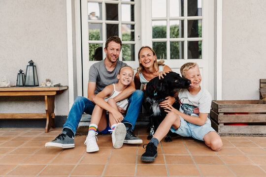 family posing in front of their home with their dog acting funny