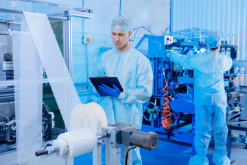 Worker use clipboard for control production line automatic machine for manufacture of medical...