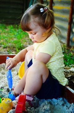 a little girl is digging in the sandbox