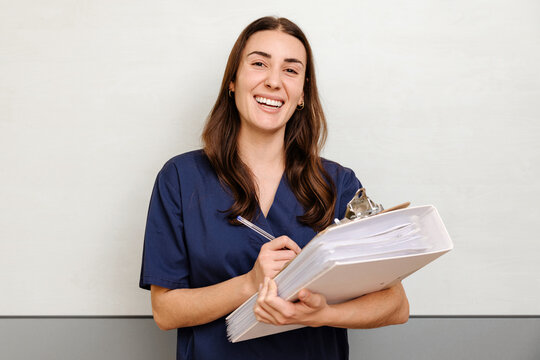 Smiling nurse with clipboard on beige background