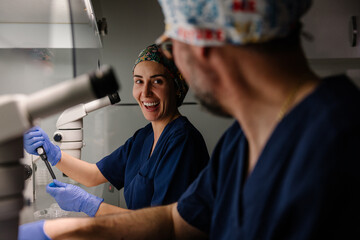 Smiling female biologist engaging in laboratory work with colleague