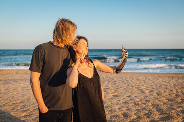 Happy couple making selfie with mobile phone at the seaside beach
