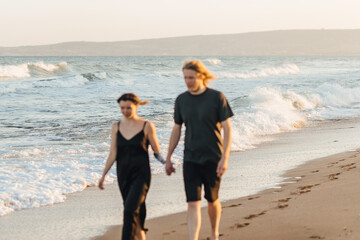 Couple walking along the ocean beach, focus on the background