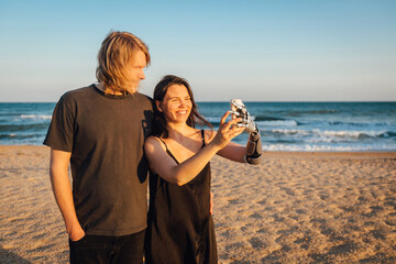 Happy couple making selfie with mobile phone at the beach on sunny day