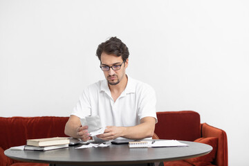 Close up of unhappy man sitting at the table, stressed and confused by calculate expense from invoice or bills, have no money to pay mortgage or loan. High prices and spending money concept