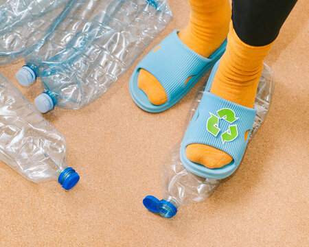 Female foot crushes a plastic bottles before sending it for recycling