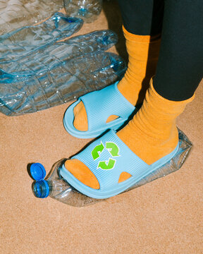 Female foot crushes a plastic bottles before sending it for recycling