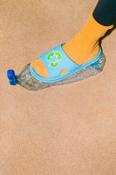 Female foot crushes a plastic bottles before sending it for recycling