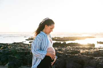 Serene pregnant woman enjoying sunset by the sea