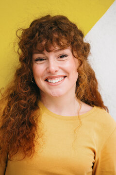 A woman's beaming smile complements her luscious golden curls