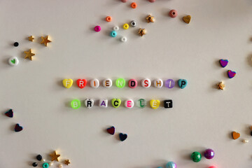 Making friendship bracelets with letter beads. Jewelry making supplies on the table. Flat lay.