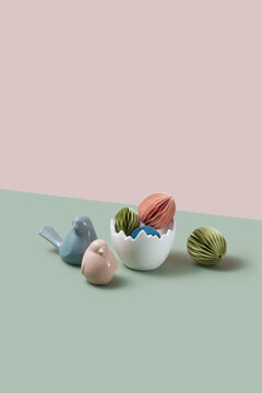 Ceramic vase filled with paper crafts next to artificial birds