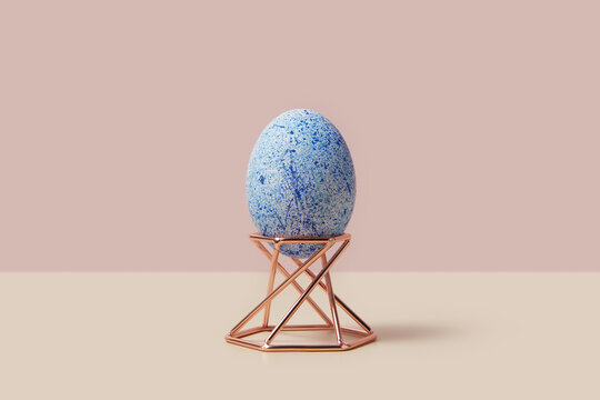 Painted with blue ornaments hen egg placed on jewellery shiny stage