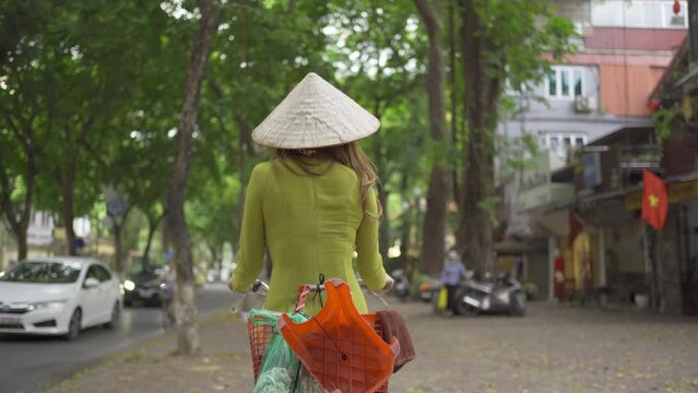 Portrait of Asian peddler with bike, Vietnamese woman girl traveling in Hanoi urban city town, Vietnam. People lifestyle.