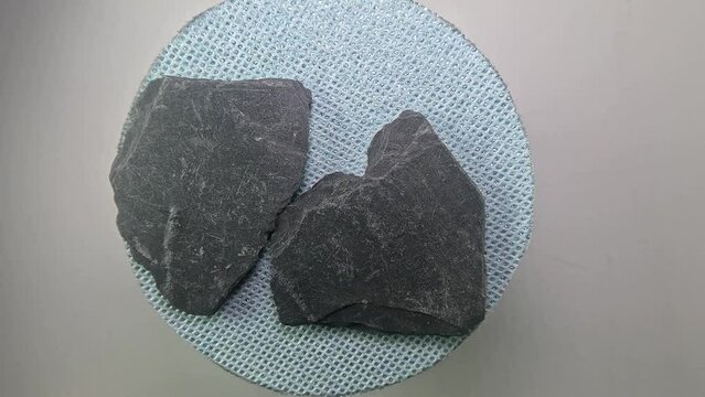 Top view of rotating gray Slate rocks on circular blue base on gray background