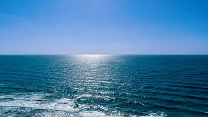 Scenic view of the sun shining over ocean waves reaching shore - Powered by Adobe