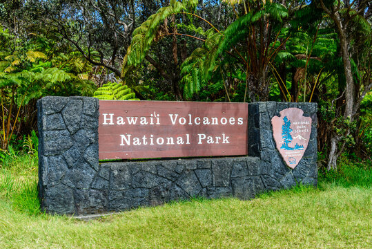 Sign for Hawaii Volcanoes National Park in front of a vibrant green meadow.