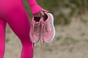 Close up of sporty woman holding her pink shoes