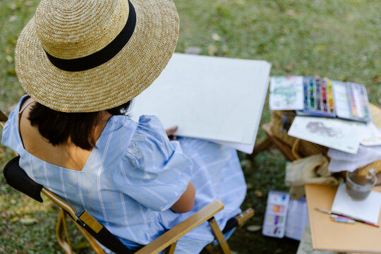 Unrecognizable woman drawing on sheet in park