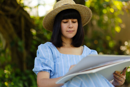 Happy woman artist painting on white sheets in park