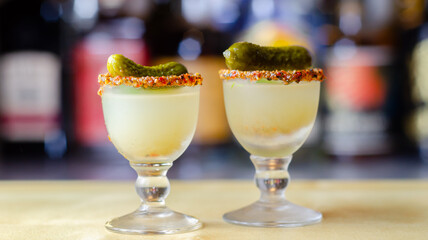 Shaken vodka and pickle juice with ice in a shot glass and garnished with small pickled cucumber and dill