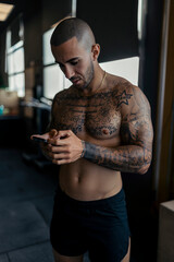 Young, tattooed male with a fit physique poses in a gym