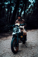 Naklejka premium Vertical shot of a man on a motorcycle parked in a forest