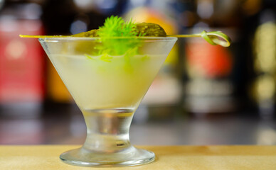 Shaken vodka and pickle juice with ice in a shot glass and garnished with small pickled cucumber and dill
