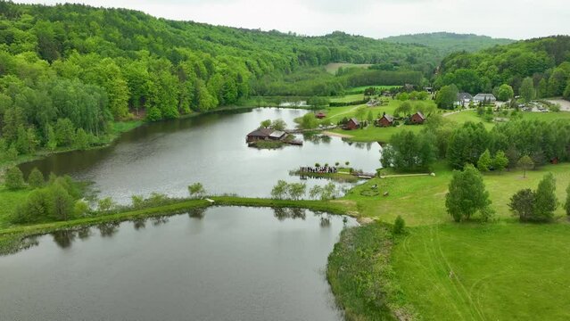 A picturesque aerial shot of a resort area near a lake with cabins, green lawns, and surrounding forested hills.