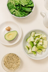 Top view of avocados, greens, and apples on a white table