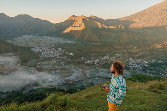 Man flying drone during the hike surrounded by volcanos on Lombok