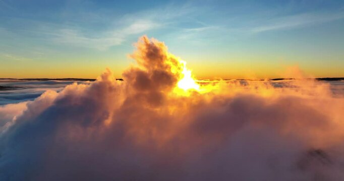 Drone timelapse of dense clouds moving in colorful sky and shiny sun in the background at sunset