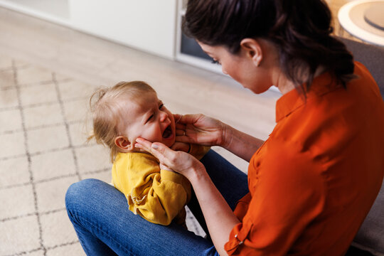 Woman consoling crying daughter at home