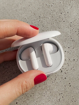 White wireless ear buds in a case in hand