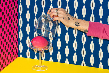 A creative still life with an artful pink dessert and a tattooed hand