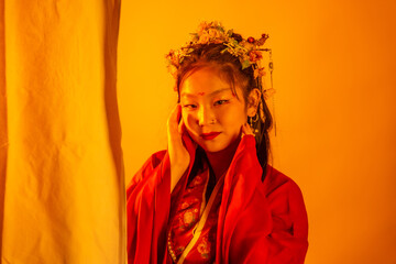 A woman in a red dress with a flower headpiece is standing in front of a white c