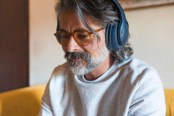Man on a sofa, wearing headphones, listening to music